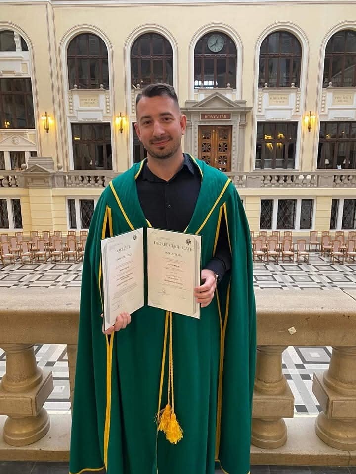 Dr. Rábai Dávid doktori talárban, a PhD-oklevelével a Debreceni Egyetem aulájában