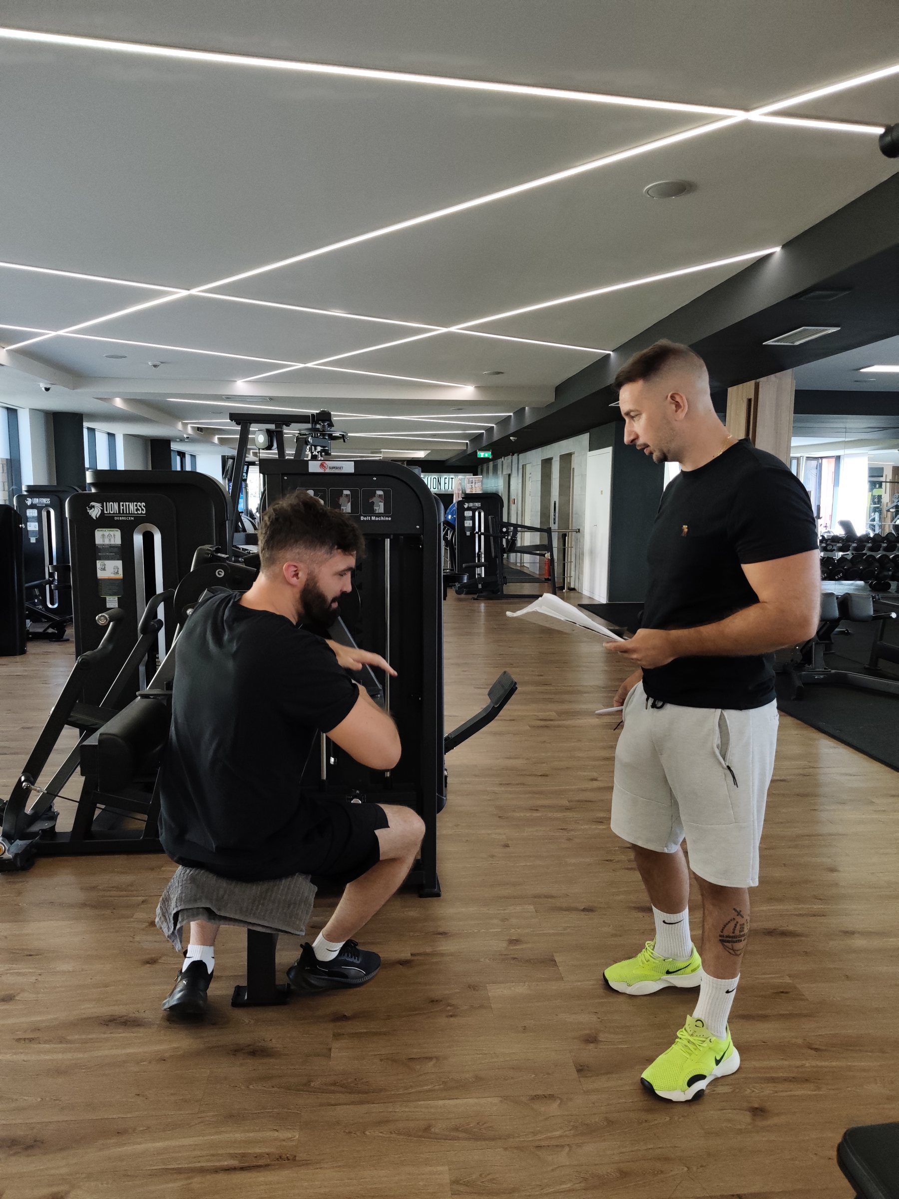 Dávid egy férfi vendégével egyezteti a következő gyakorlatot a Lion Fitnessben